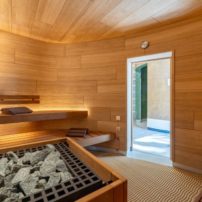 Sauna mit gerundeter Wand, großem Saunaofen und beleuchtetem Wandmotiv