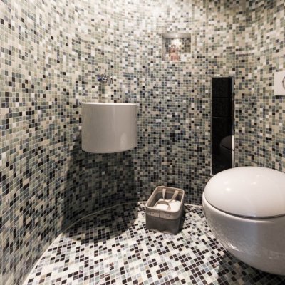 Ein mit Mosaikfliesen verkleidetes, kleines WC mit runden Wänden